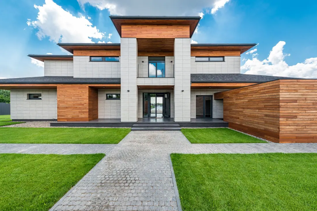 Contemporary two-storey house with timber and pale stone cladding under a blue sky